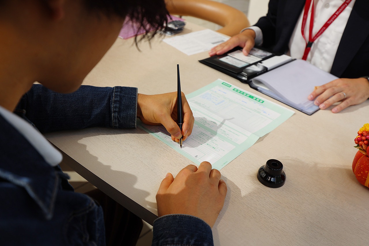 手続きの終わりに車両確認・受領書へサイン。緊張で手が震えるカナタ
