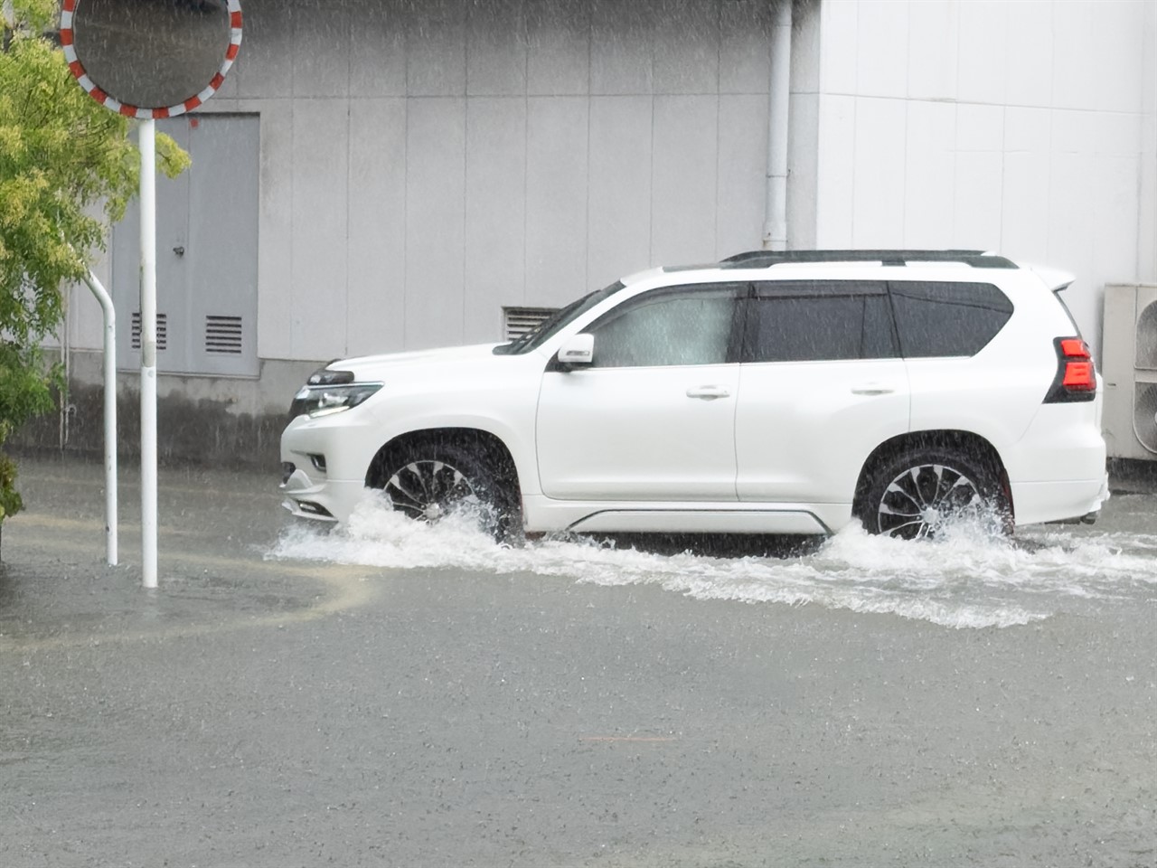 冠水した道路で車が水しぶきを上げながら走行する様子